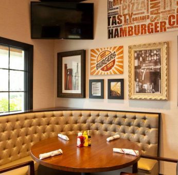 The Burger Place is Sonesta Atlanta Airport South’s on-site restaurant, and includes burger-related art on the wall alongside a widescreen TV, and large windows.