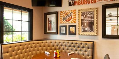 The Burger Place is Sonesta Atlanta Airport South’s on-site restaurant, and includes burger-related art on the wall alongside a widescreen TV, and large windows.