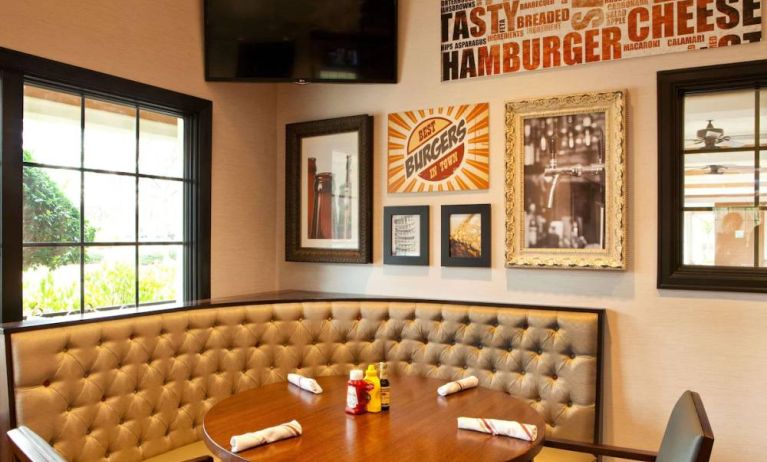 The Burger Place is Sonesta Atlanta Airport South’s on-site restaurant, and includes burger-related art on the wall alongside a widescreen TV, and large windows.