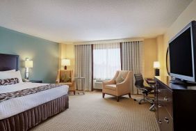 Sonesta Atlanta Airport North double bed guest room, including armchairs, window, and a television.