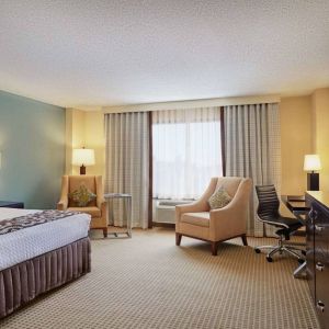 Sonesta Atlanta Airport North double bed guest room, including armchairs, window, and a television.