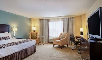 Sonesta Atlanta Airport North double bed guest room, including armchairs, window, and a television.