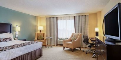 Sonesta Atlanta Airport North double bed guest room, including armchairs, window, and a television.