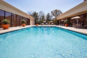 The hotel’s outdoor pool has potted plants by the side, in addition to shaded tables and chairs.