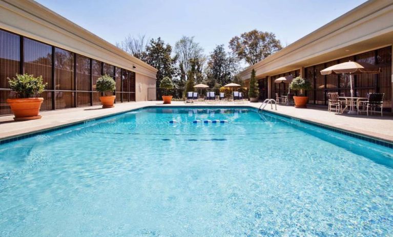 The hotel’s outdoor pool has potted plants by the side, in addition to shaded tables and chairs.