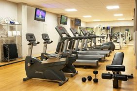 The fitness center at Sonesta Atlanta Airport North includes plenty of towels, free weights, and various types of exercise machines, plus multiple wall-mounted TVs.