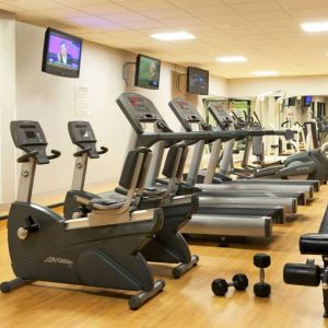 The fitness center at Sonesta Atlanta Airport North includes plenty of towels, free weights, and various types of exercise machines, plus multiple wall-mounted TVs.