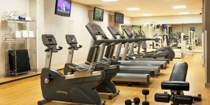 The fitness center at Sonesta Atlanta Airport North includes plenty of towels, free weights, and various types of exercise machines, plus multiple wall-mounted TVs.