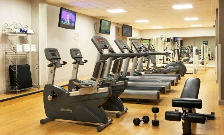 The fitness center at Sonesta Atlanta Airport North includes plenty of towels, free weights, and various types of exercise machines, plus multiple wall-mounted TVs.