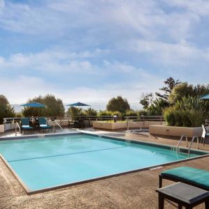 Sonesta San Jose’s outdoor pool has an adjacent hot tub, with tables and chairs, and sun loungers, nearby.