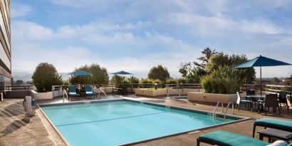 Sonesta San Jose’s outdoor pool has an adjacent hot tub, with tables and chairs, and sun loungers, nearby.