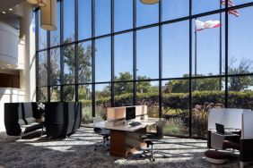 The hotel’s business center has a wall of windows next to it with a view of greenery and flags, while the center itself features multiple workstations and nooks for guests to use.