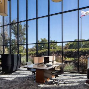 The hotel’s business center has a wall of windows next to it with a view of greenery and flags, while the center itself features multiple workstations and nooks for guests to use.