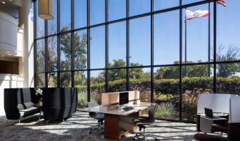 The hotel’s business center has a wall of windows next to it with a view of greenery and flags, while the center itself features multiple workstations and nooks for guests to use.