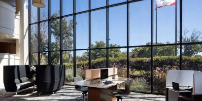 The hotel’s business center has a wall of windows next to it with a view of greenery and flags, while the center itself features multiple workstations and nooks for guests to use.