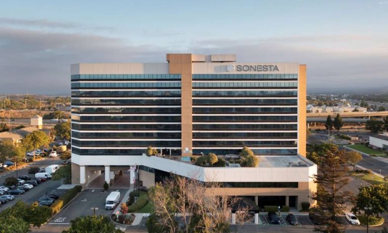 Sonesta San Jose’s exterior has ample parking for guests, abundant greenery, and a pool, plus the hotel chain’s name on the outside of the top floor.