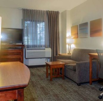 Guest room living area in Sonesta ES Suites Anaheim Resort Area, furnished with sofa and television, plus a workspace desk and chair.