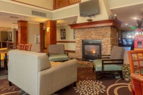 Sonesta ES Suites Anaheim Resort Area’s lobby is furnished with sofa and armchair seating around a widescreen television and fireplace.