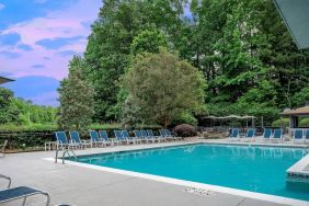 The outdoor pool at Sonesta Charlotte Executive Park has chairs by the side, is close to the fire pit, and connects directly to the indoor pool.