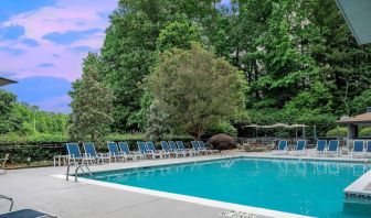 The outdoor pool at Sonesta Charlotte Executive Park has chairs by the side, is close to the fire pit, and connects directly to the indoor pool.