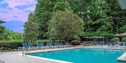 The outdoor pool at Sonesta Charlotte Executive Park has chairs by the side, is close to the fire pit, and connects directly to the indoor pool.