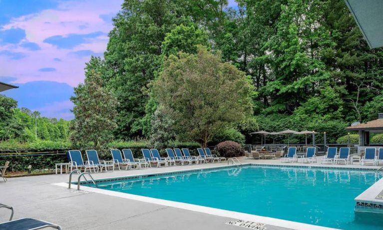 The outdoor pool at Sonesta Charlotte Executive Park has chairs by the side, is close to the fire pit, and connects directly to the indoor pool.