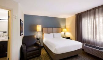 Sonesta Simply Suites St Louis Earth City double bed guest room, featuring armchair, window, and ensuite bathroom.