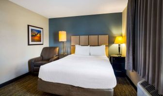 Sonesta Simply Suites St Louis Earth City double bed guest room, featuring bedside lamps, window, and armchair.