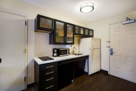 Sonesta Simply Suites St Louis Earth City guest room kitchen, complete with array of cupboards and drawers, plus a hob, microwave, and fridge-freezer.