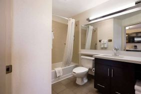 Guest bathroom in Sonesta Simply Suites St Louis Earth City, with bath, lavatory, long mirror, and sink.