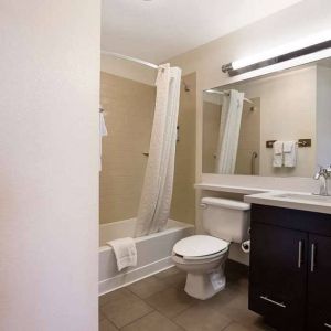 Guest bathroom in Sonesta Simply Suites St Louis Earth City, with bath, lavatory, long mirror, and sink.