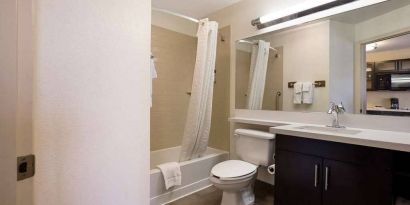 Guest bathroom in Sonesta Simply Suites St Louis Earth City, with bath, lavatory, long mirror, and sink.