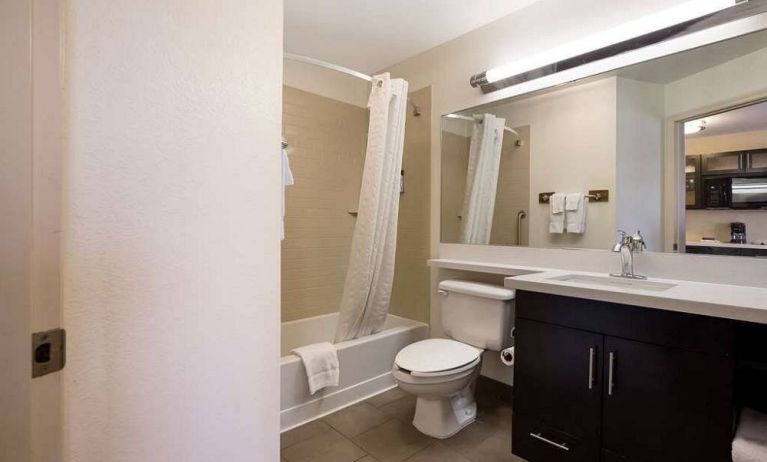 Guest bathroom in Sonesta Simply Suites St Louis Earth City, with bath, lavatory, long mirror, and sink.