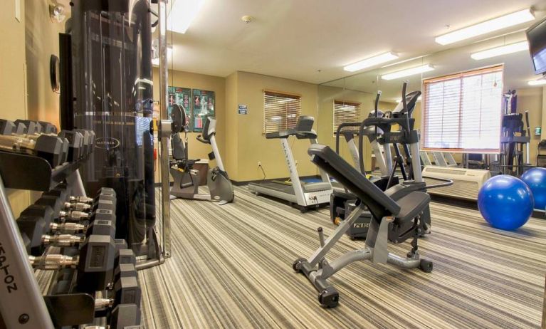 Sonesta Simply Suites St Louis Earth City’s fitness center has rows of free weights, gym balls, a TV, and assorted types of exercise machinery.