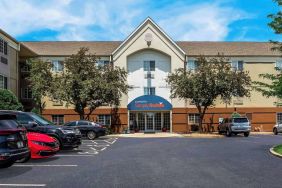 Sonesta Simply Suites St Louis Earth City’s exterior includes numerous parking spaces (including disabled spaces near the covered entrance) and trees.