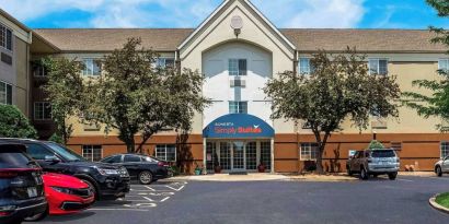 Sonesta Simply Suites St Louis Earth City’s exterior includes numerous parking spaces (including disabled spaces near the covered entrance) and trees.