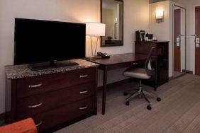 Sonesta Chicago O'Hare Airport Rosemont guest room workspace, including desk, chair, lamp, telephone, and nearby TV.