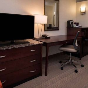 Sonesta Chicago O'Hare Airport Rosemont guest room workspace, including desk, chair, lamp, telephone, and nearby TV.