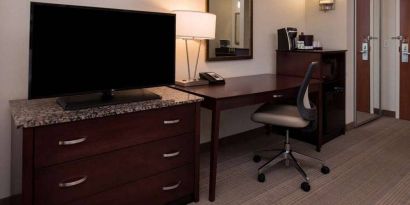 Sonesta Chicago O'Hare Airport Rosemont guest room workspace, including desk, chair, lamp, telephone, and nearby TV.