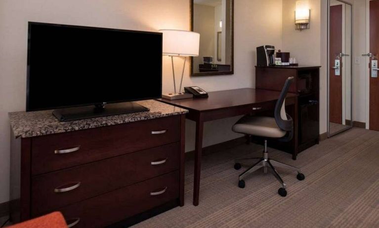 Sonesta Chicago O'Hare Airport Rosemont guest room workspace, including desk, chair, lamp, telephone, and nearby TV.