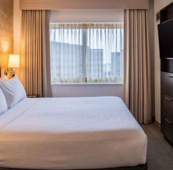 Sonesta Chicago O'Hare Airport Rosemont double bed guest room with window and wall-mounted TV.