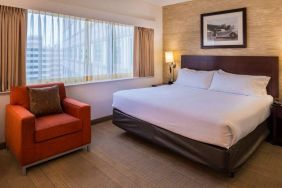 Double bed guest room in Sonesta Chicago O'Hare Airport Rosemont, including window, bedside light, and an armchair.