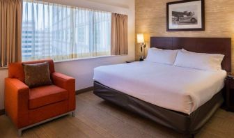 Double bed guest room in Sonesta Chicago O'Hare Airport Rosemont, including window, bedside light, and an armchair.