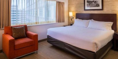 Double bed guest room in Sonesta Chicago O'Hare Airport Rosemont, including window, bedside light, and an armchair.