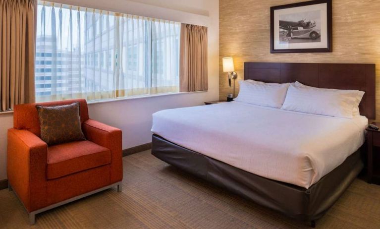 Double bed guest room in Sonesta Chicago O'Hare Airport Rosemont, including window, bedside light, and an armchair.