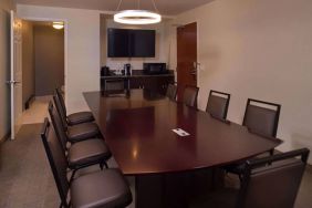 Meeting room in Sonesta Chicago O'Hare Airport Rosemont, featuring long wooden table, 10 chairs, a microwave, and a large TV.