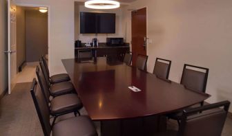 Meeting room in Sonesta Chicago O'Hare Airport Rosemont, featuring long wooden table, 10 chairs, a microwave, and a large TV.