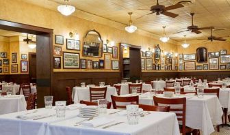 The hotel restaurant has white tablecloths, ceiling fans, and walls brimming with mirrors and photographs.