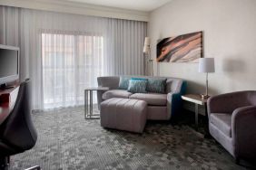 Sonesta Select Newport Middletown guest room living area, furnished with armchair, TV, coffee tables, and a sofa.