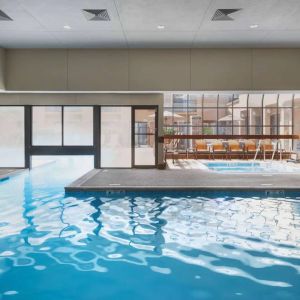 The hotel’s indoor pool has an adjacent hot tub and large windows, with a direct water link to the outdoor pool. 